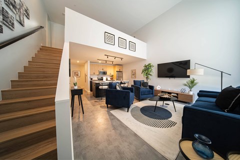 a living room with couches and chairs and a staircase